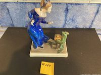 Full figurine angled view on black background displaying woman and frog