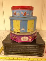 Stacked view of three tins showing designs and size relation