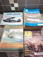 Stacks of Sport Aviation, Canadian Aviation, Flying and Air Classics magazines with handwritten date-range notes