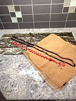 All four items laid out: sequined scarf, chiffon scarf, red glass bead necklace, brown seed bead necklace