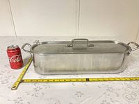 Pan with lid beside soda can and tape for scale