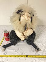 Full view of seated fabric fantasy creature with measuring tape and soda can for scale