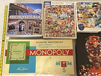 Overview showing Coronation Street game tin, The 1980s puzzle, Globetrotter World puzzle, Monopoly box
