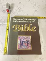 Front cover of hardcover book with tape measure showing roughly 11 inches tall