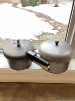 Pressure cooker and cooking pot side by side on windowsill