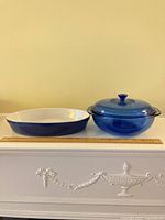 Both casserole with lid and oval baker on surface with ruler for scale