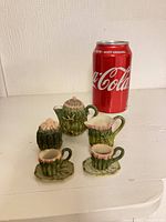 Full view of miniature tea set next to Coke can