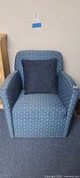 Front view of blue woven club armchair with navy pillow
