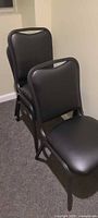 Three black vinyl stackable chairs side view