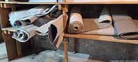 Multiple carpet rolls stored on wooden shelves