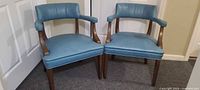 Front view of both light blue vinyl armchairs with wooden frames
