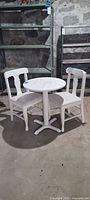 Full view of round white painted table and two chairs