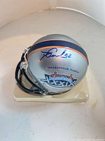 Signed side view of mini helmet showing autograph, stripe and logo