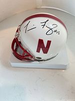 Left side view of signed Nebraska mini helmet on base