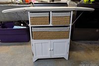 Front view of cabinet with ironing board extended and baskets visible