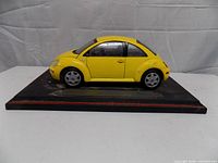 Left side view of yellow Volkswagen New Beetle model on black base