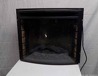 front view of black electric fireplace insert with curved glass and faux logs