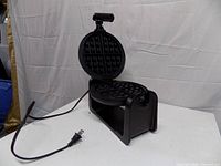 Waffle maker open showing non-stick plates and cord