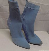 Front view of both light blue sock boots showing knit texture, rhinestone detailing, pointed toes, stiletto heels