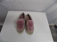 Top view of both sneakers showing pom-poms and general wear