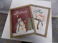 Front view showing both framed wall signs with snowman designs and text