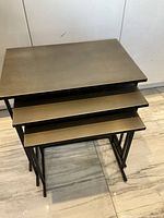 Three nesting tables stacked, top view showing bronze tops and iron legs