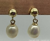 Front view of both gold and pearl drop earrings hanging