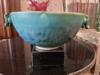 Side view of turquoise pottery bowl showing glaze and one handle