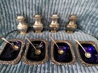 Front view of four salt shakers, four cellars with spoons inserted