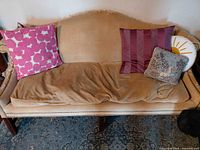 Front view of couch with pillows, showing upholstery and nailhead trim