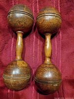 Full view of both wooden dumbbells on red fabric