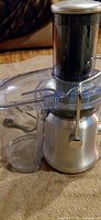 Front view of Breville juicer showing stainless base, clear cover, pulp container