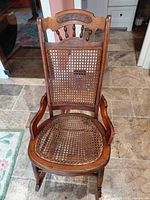 Front view of wooden child rocking chair showing cane seat and back