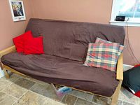 Futon with brown cover and throw pillows in room