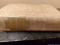 Spine and cloth cover showing beige linen and gilt title