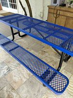 Angled view of one side of blue expanded-metal picnic table with attached bench