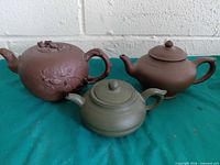 Front view of three teapots showing colors, shapes, decoration