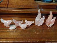 Seven rose quartz bird figurines arranged on wood surface