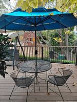 Full view of patio set showing table, four chairs and blue umbrella