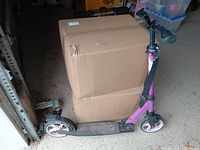 Scooter standing folded next to box showing full side profile and color