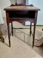 Front view of dark wood telephone table showing open shelf and turned legs