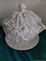 Covered white cabbage-leaf ceramic tureen with underplate