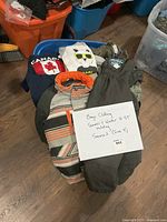 Pile of boys clothing including winter jacket, snow pants, sweatshirts and tees