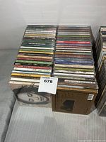 Two tall stacks of compact discs in jewel cases with one cardboard-sleeve CD at front