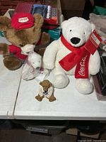 Large Coca-Cola plush bear, Co-op plush bear, small bagged Coca-Cola plush, resin bear figurine on table