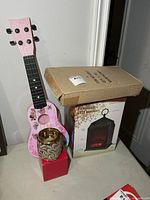 All four items together showing guitar, candle holder, cardboard clock box, LED lantern box