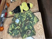 Camo dog coat and black/yellow costume on table