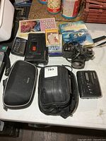 Overview of all electronics, camera, cassette player, tapes, trail camera and cases on table