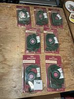 Seven packaged Epicord green extension cords on table