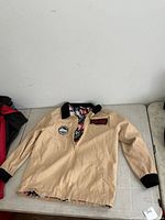 Full front view of tan Ghostbusters jacket on table